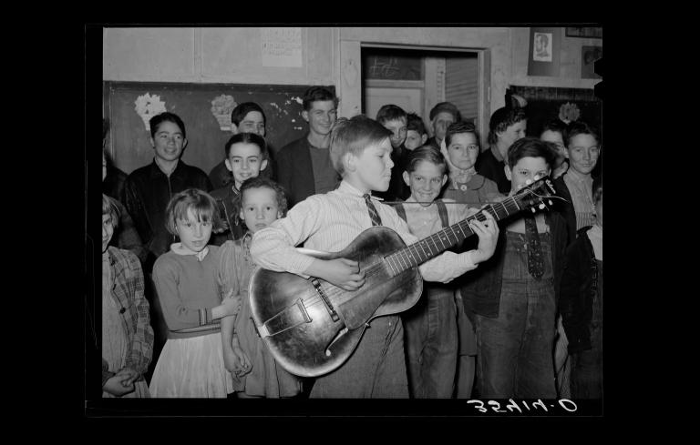 A boy playing and singing “Sipping Cider Through a Straw” at a pie supper in Muskogee County, Oklahoma, USA, 1940.